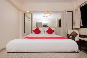 a bedroom with a large white bed with red pillows at Super Hotel O Solitaire in Turambhe +25 photos