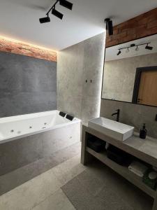 a bathroom with a tub and a sink and a mirror at Sadowa Ostoja z prywatnymi jacuzzi in Pierwoszyno +22 photos