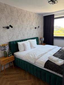 a large bed with a green headboard in a bedroom at Sadowa Ostoja z prywatnymi jacuzzi in Pierwoszyno