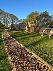 a park with a bench and grass and a fence at Spinney Wood Glamping, Oak Hut in Bewdley