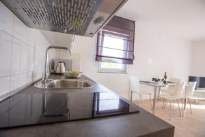 a kitchen with a sink and a table with chairs at Apartments Sesar in Rab