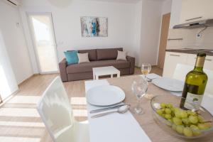 a room with a table with a bottle of wine and a bowl of fruit at Apartments Sesar in Rab