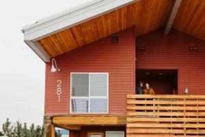 two people standing on the porch of a red house at Mt Merritt Suite Boutique Hotel Experience in Kalispell