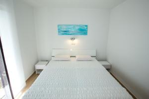 a white room with a bed with two pillows at Apartments Sesar in Rab
