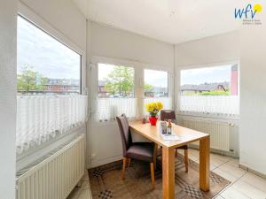 a dining room with a table and chairs and windows at Haus Wilhelm-Feldhoff Ferienwohnung Veen in Borkum