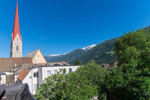 a view of a town with a church and mountains at Moar Apartments in Silandro