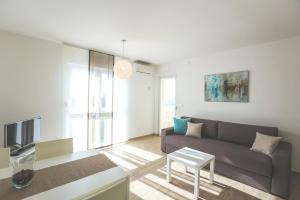 a living room with a couch and a tv at Apartments Sesar in Rab
