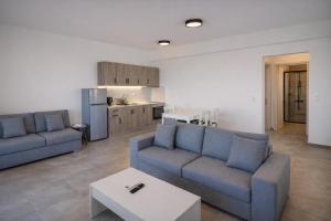 a living room with two blue couches and a kitchen at Aroniadika rooms in Kythira