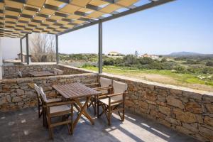 a patio with a table and chairs and a stone wall at Aroniadika rooms in Kythira