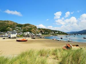 a beach with boats in the water and houses at Leamington House in Barmouth