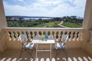 a balcony with a table and chairs and a large window at Apartments Sesar in Rab