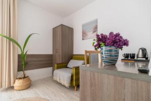 a room with a table with a vase of purple flowers at DOM GOŚCINNY ROMA in Rewal