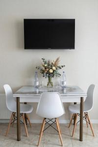 a table with white chairs and a vase of flowers at Central cozy apartments- one and two bedrooms option in Chişinău