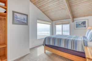 a bedroom with a bed and two windows at Breakers Beach House 7 in Neskowin