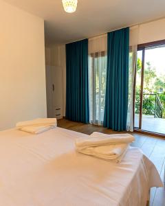 a bedroom with a large white bed with blue curtains at Doğa Pansiyon in Marmaris