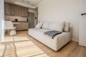 a living room with a white couch and a kitchen at Nida Breeze Apartments in Neringa
