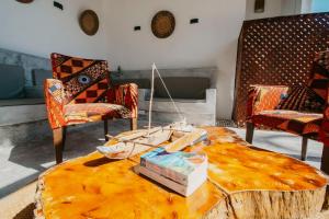a room with a table and chairs and a coffee table with a tree stumpiqueness at Aquelia Rose Hotel in Jambiani