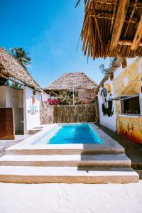 a swimming pool in front of a house at Aquelia Rose Hotel in Jambiani