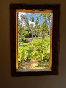 a window with a view of a garden with palm trees at Retiro Real in Santo Antônio do Leite