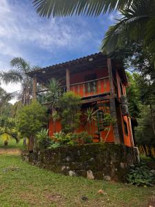 an orange house with a stone wall in front of it at Retiro Real in Santo Antônio do Leite