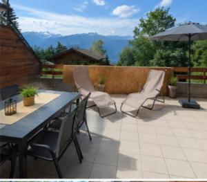 a patio with a table and chairs and an umbrella at Le Cormier - Appartement 6 personnes in Ovronnaz