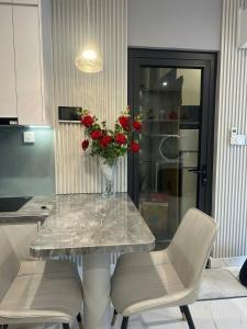 a table and two chairs with a vase of red roses at Alex Vinhomes Grand in Gò Công +1 photo
