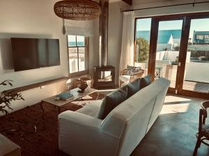 a living room with a white couch and a television at Duneberry Beach Studio in Yzerfontein