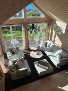 a living room with couches and tables and windows at Haukland beach panorama - with Sauna in Offersøya