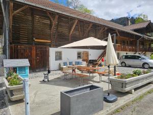 a patio with a table and a umbrella and a car at Burgbühler Guesthouse in Lenk