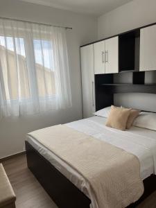 a bedroom with a large bed with white sheets and windows at Apartments & Rooms Alagić in Makarska