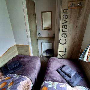 a bedroom with two beds and a mirror on the wall at KL Caravan in Prestatyn +16 photos