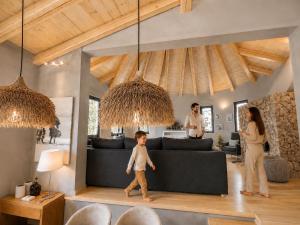 a young child walking in a living room with two adults at Le Blanc in Dassia