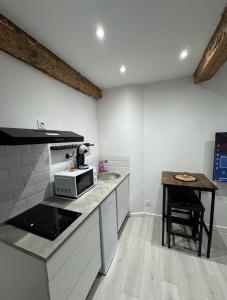 a kitchen with a counter with a microwave and a table at Les Perles de Limoux -Studio Centre Climatiseur Wifi Parking Gratuit in Limoux +5 photos