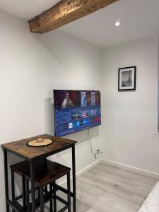 a room with a table and a tv on a wall at Les Perles de Limoux -Studio Centre Climatiseur Wifi Parking Gratuit in Limoux