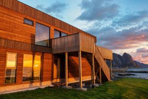 a wooden building with a sunset in the background at Reine Sea Apartment in Moskenes