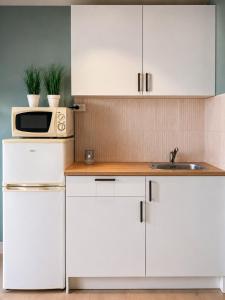 a white kitchen with a microwave and a sink at Reine Sea Apartment in Moskenes +31 photos