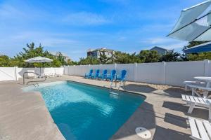 a swimming pool with blue chairs and a fence at Little Cayman in Salvo