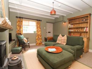 a living room with a green couch and a table at The Cooks Cottage in Malton