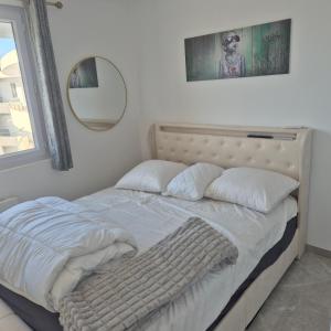 a bed with white sheets and pillows in a bedroom at Appartement neuf full équipe in Palavas-les-Flots