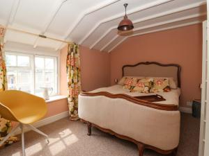 a bedroom with a bed and a chair and a window at The Cooks Cottage in Malton