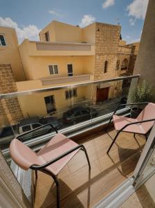 two chairs on a balcony with a view of a building at New Apartment - 3 min to Airport - 10 min to Valletta in Gudja