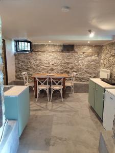 a table and chairs in a room with a stone wall at Kamara 1898 katoi in Mouresi