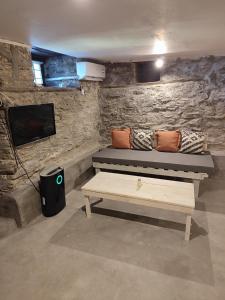 a room with a bench and a tv and a table at Kamara 1898 katoi in Mouresi