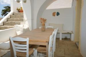 a dining room with a wooden table and white chairs at Rocky Beach House in Kythira +47 photos