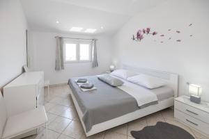 a white bedroom with a large bed and a window at Apartments Baretić in Crikvenica +61 photos