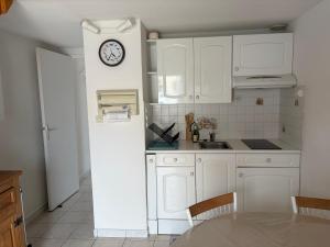 a kitchen with white cabinets and a clock on the wall at 225 rue de la source in Bretignolles-sur-Mer +5 photos