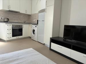a kitchen with white cabinets and a flat screen tv at Casa Ducrate by Asterisco Secular in Crato