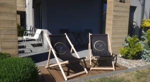 two chairs sitting on a porch next to a house at Apartament MyMoment in Tupadła +5 photos
