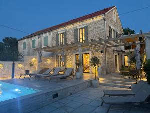 a villa with a swimming pool in front of a building at Heritage Villa Francheza-Elegant Stone villa near the Beach, Pašman Island , Ugrinić in Ugrinići