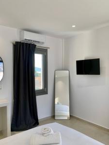 a room with a mirror and a window and a television at AiΘeria Suites Ios in Ios Chora